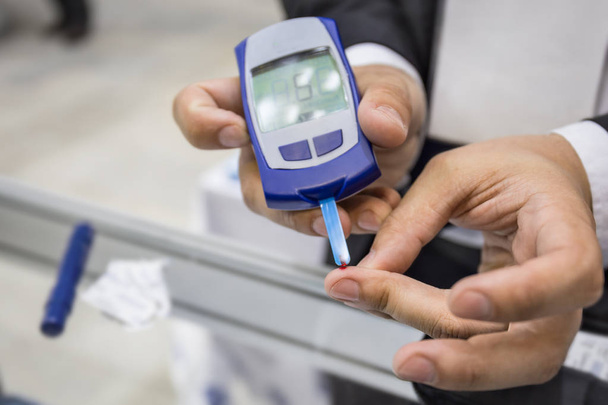 Glucometro. L'uomo controlla il livello di zucchero nel sangue test dal sangue da dito, malattia diabetica
 - Foto, immagini