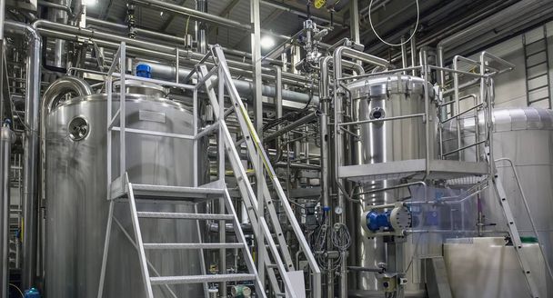 Nerezové zařízení pro piva: velké nádrže a potrubí v továrně na moderní pivo. Produkce pivovaru, průmyslové pozadí - Fotografie, Obrázek
