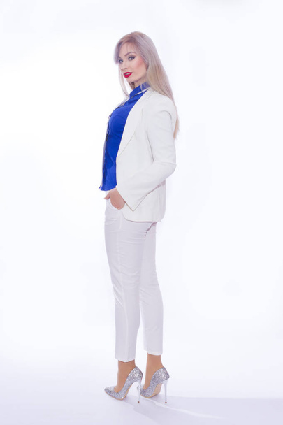 Full-length studio portrait of a business woman in a white pants suit and silver high-heeled shoes - Foto, Bild