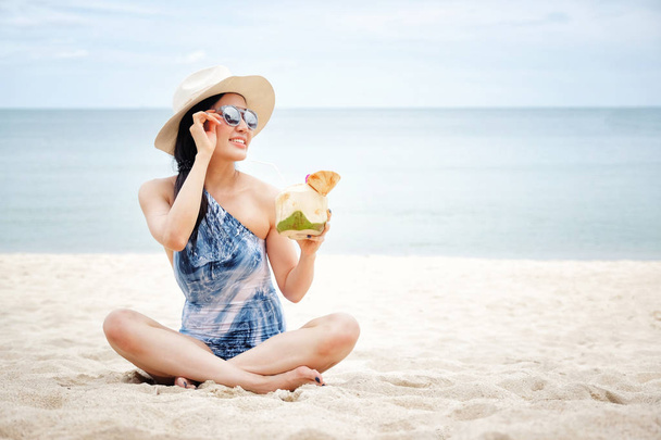 Happy woman with fresh coconut water on the beach - Photo, Image