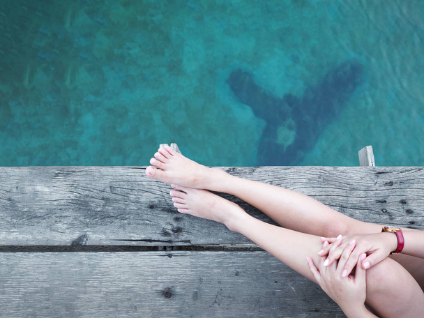 Close-up van vrouw been en voet over de blauwe zee. - Foto, afbeelding