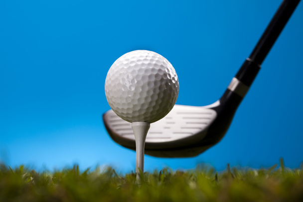 Golf ball on green grass over a blue background - Foto, afbeelding
