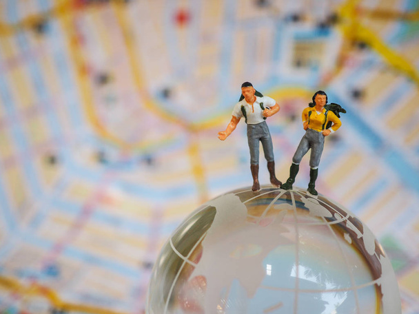 Miniature traveller or backpacker stand on globe of glass and ma - Photo, Image