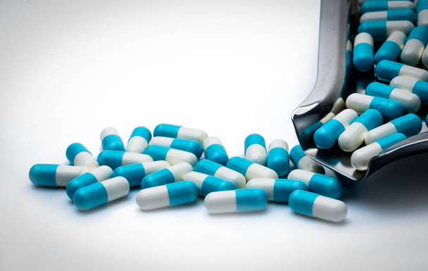 Μπλε και άσπρο κάψουλες χάπια και ναρκωτικών θήκη σε λευκό φόντο με αντίγραφο χώρου για το κείμενο. Σφαιρική σύλληψη της υγειονομικής περίθαλψης. Αντιβιοτικά ναρκωτικών αντίσταση έννοια. Αντιμικροβιακή καψάκιο χάπια. - Φωτογραφία, εικόνα