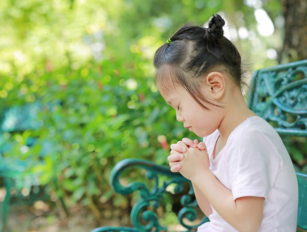 Little child girl praying in the garden - Fotó, kép