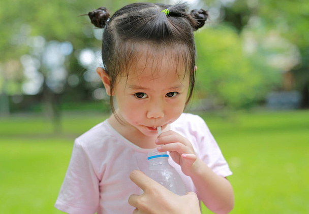 Little girl drinking water in the park. Portrait outdoor. - Фото, изображение