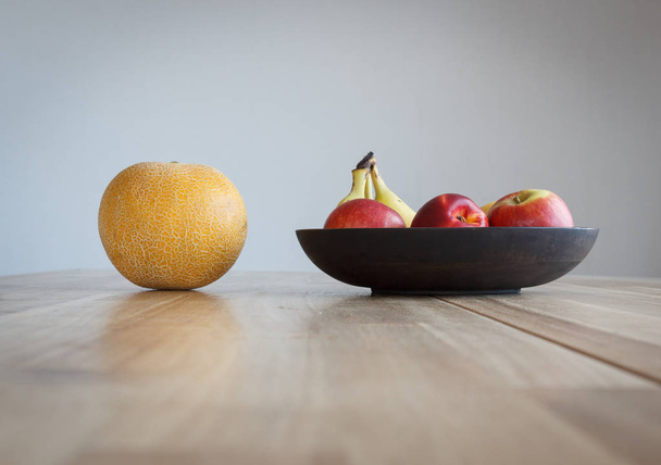 Pyöreä keltainen meloni ja muut hedelmät puupöydällä
. - Valokuva, kuva