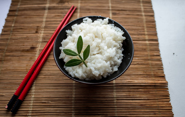 тарелка риса и палочки для еды на ковре из бамбуковых палочек
 - Фото, изображение