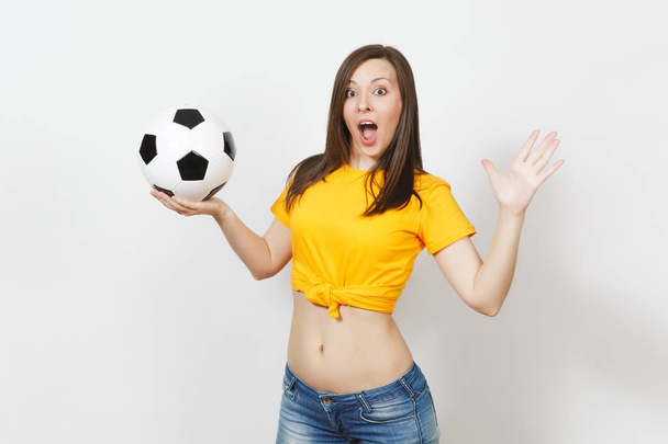 Beautiful European young strong slim sexy woman, football fan or player in yellow uniform holding soccer ball isolated on white background. Sport, play football, health, healthy lifestyle concept. - Photo, Image