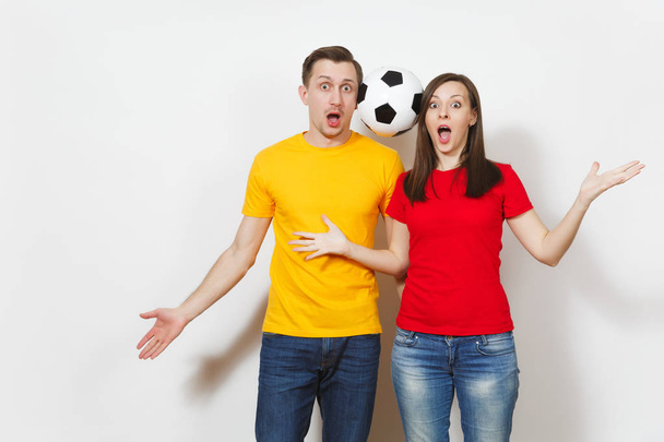 Fun crazy cheerful European young couple, woman, man, football fans in yellow red uniform hold play soccer ball isolated on white background. Sport, game football, family leisure, lifestyle concept. - Photo, Image