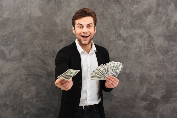 Cheerful young businessman holding money looking camera. - Foto, Imagen