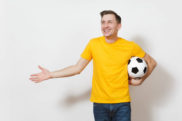 インスピレーション若いヨーロッパ人やファンは黄色いユニフォームで選手サッカー ボールを保持する手を広げる、白い背景で隔離の好きなサッカー チームを応援します。スポーツ サッカー、健康的なライフ スタイルのコンセプト. - 写真・画像