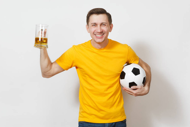 inspirierte junge lustige fröhliche europäische Mann, Fan oder Spieler in gelben Uniform halten Pint Becher Bier, Fußballball jubeln Lieblings-Fußballmannschaft isoliert auf weißem Hintergrund. Sport, Spiel, Lifestyle-Konzept. - Foto, Bild
