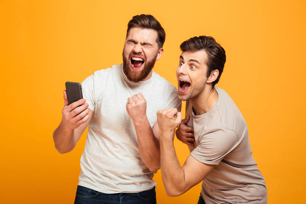 Image of two bachelors screaming and rejoicing win of football t - Foto, afbeelding