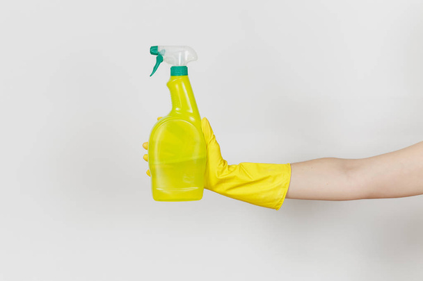 El primer plano de la mano femenina en guantes amarillos sostiene la botella de aerosol amarillo con líquido más limpio con lugar para el texto aislado sobre fondo blanco. Concepto de artículos de limpieza. Copiar espacio para publicidad
 - Foto, Imagen