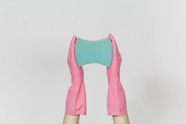 Zbliżenie na kobiece dłonie w różowe rękawiczki poziome posiada niebieski dużej gąbki do czyszczenia i mycia naczyń na białym tle na białym tle. Czyszczenie koncepcji zaopatrzenia. Miejsce na reklamę - Zdjęcie, obraz