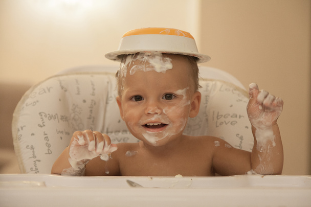 Το παιδί αλείψει με τα τρόφιμα και βάλτε ένα πιάτο στο κεφάλι του.  - Φωτογραφία, εικόνα