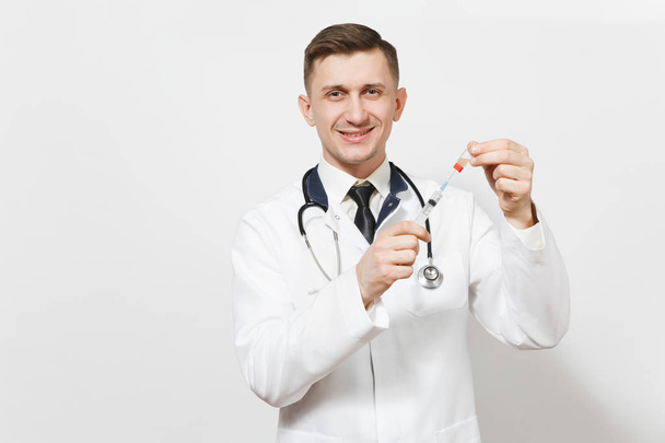 Усміхнений молодий лікар ізольований на білому тлі. Чоловік-лікар в медичній формі, стетоскоп малює рідку медицину з пляшки шприцом з голкою. Медичний персонал, концепція медицини
. - Фото, зображення