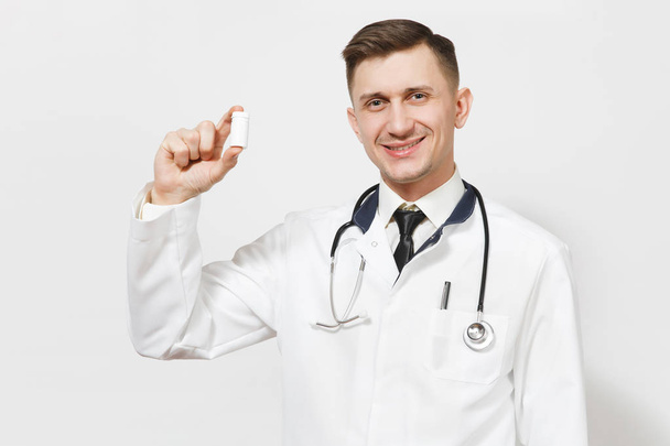Uśmiechnięty człowiek doświadczony przystojny młody lekarz na białym tle. Lekarz w medyczny stetoskop jednolite, trzymając butelkę z białe tabletki. Pracowników służby zdrowia, zdrowia, medycyny pojęcie. - Zdjęcie, obraz