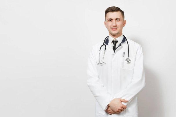 Serious confident experienced handsome young doctor man isolated on white background. Male doctor in medical gown, shirt and tie, stethoscope looking camera. Healthcare personnel, medicine concept. - Photo, Image