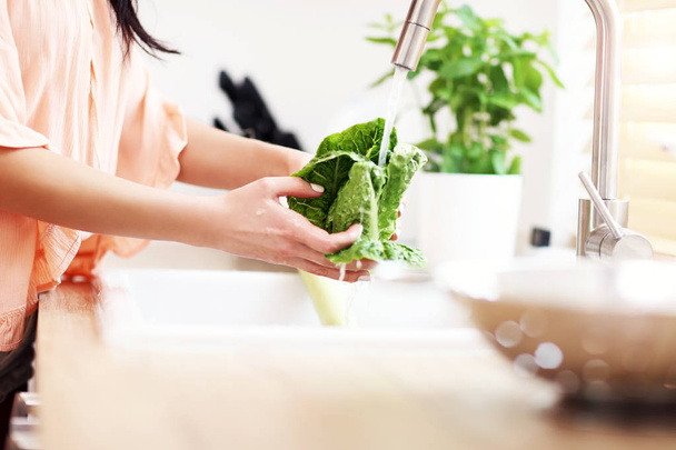 Young woman washing lettuce in modern kitchen - Φωτογραφία, εικόνα