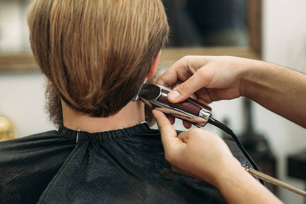Vousatý muž v kadeřnictví s vlasy nůžky - Fotografie, Obrázek