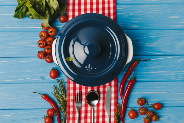 вид сверху на голубую сковороду и овощи на голубом столе
 - Фото, изображение