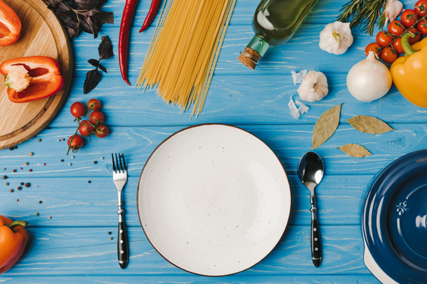 vista superior del plato vacío y los ingredientes en la mesa azul
 - Foto, Imagen