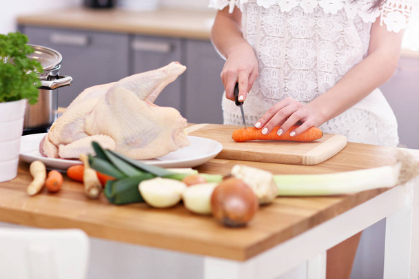 Νεαρή γυναίκα προσπαθεί να προετοιμάσει σούπα κοτόπουλου στην κουζίνα - Φωτογραφία, εικόνα