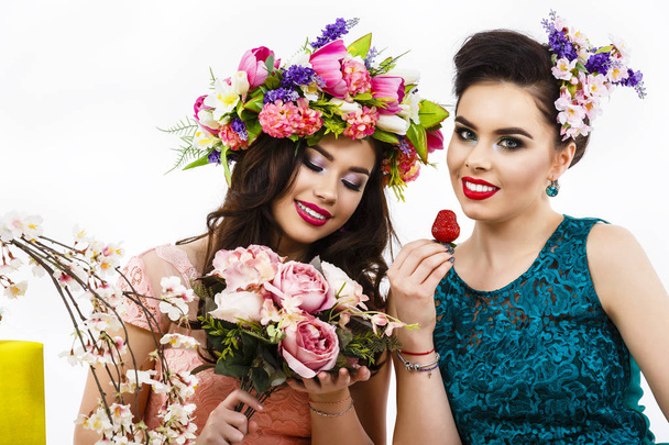 Two beautiful girl friends with strawberries and decoration flow - Photo, Image
