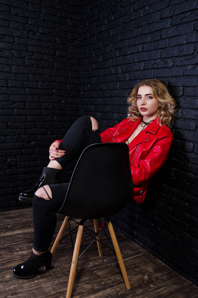 Studio portrait of blonde girl in red leather jacket posed on ch - Fotoğraf, Görsel