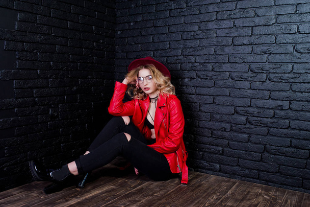 Studio portrait of blonde girl with red hat, glasses and leather - 写真・画像