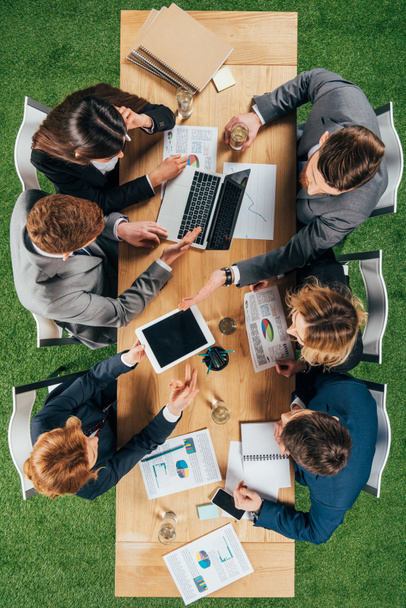 Vista superior de los colegas de negocios que trabajan en la mesa con el ordenador portátil, smartphone y tableta en la oficina
 - Foto, imagen