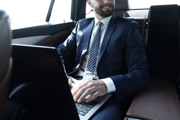 man with laptop sitting in the back seat in the car - Photo, Image