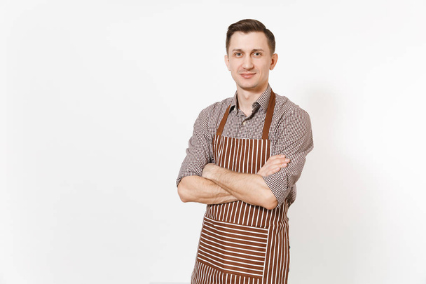 Young confident man chef or waiter holding hands crossed in striped brown apron, shirt isolated on white background. Male housekeeper or houseworker looking camera. Domestic worker for advertisement. - Photo, Image