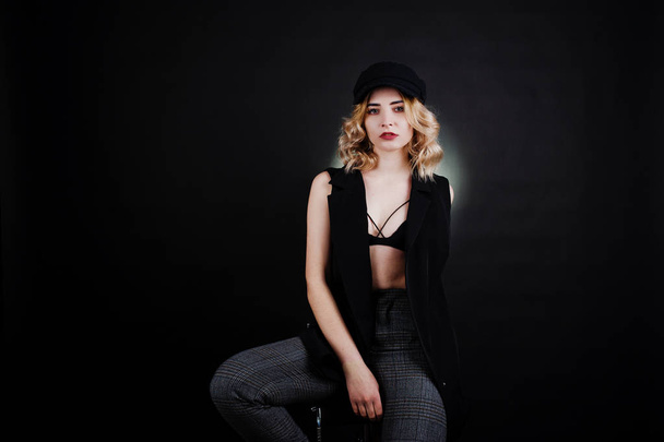 Studio portrait of blonde girl in black wear, bra and cap agains - Fotografie, Obrázek
