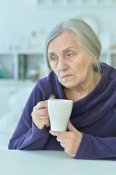 Portrait of a sad old woman drinking tea - Fotoğraf, Görsel