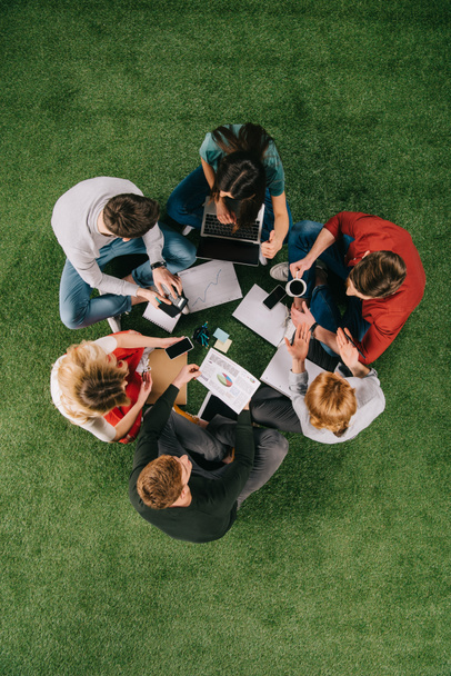 Top view of businesspeople working with devices and documents on grass - Zdjęcie, obraz