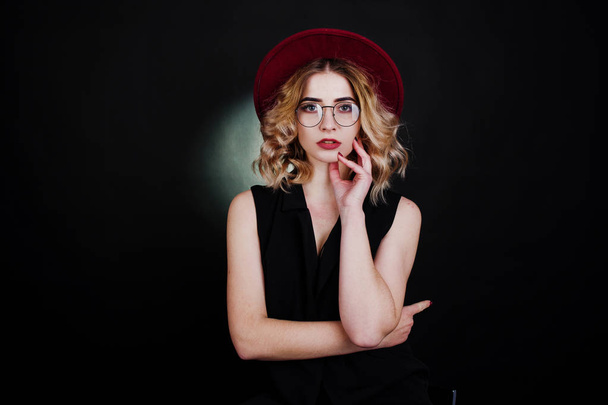 Studio portrait of blonde girl in black wear, red hat and glasse - Photo, Image