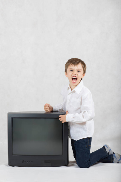 Il ragazzo di sette anni vuole distruggere una vecchia TV. Spazio libero per un testo
. - Foto, immagini