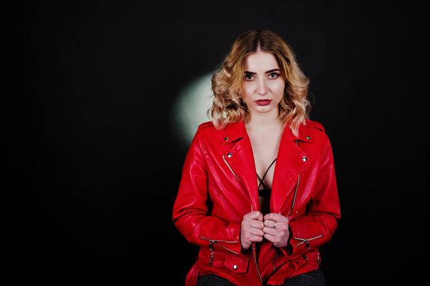 Studio portrait of blonde girl in red leather jacket against bla - 写真・画像