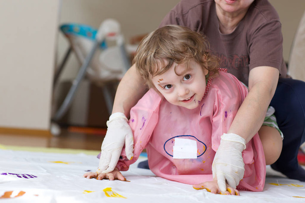 4-jähriges Kind bemalt weiße Decke mit Handflächen - Foto, Bild