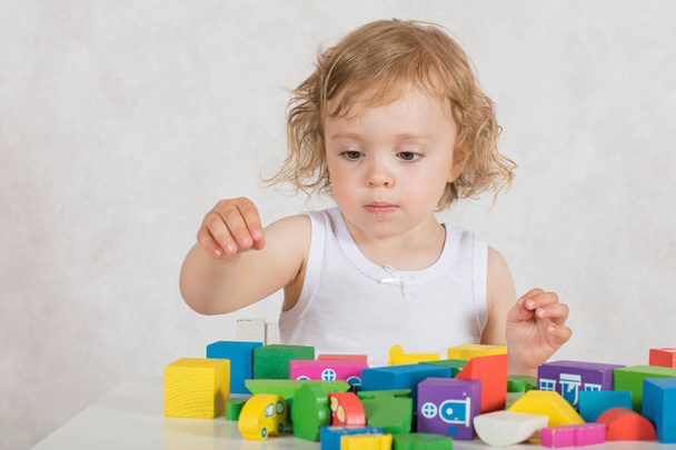 Malá dívka dvou let buduje něco z barevných geometrických tvarů a obrazců. Closeup - Fotografie, Obrázek