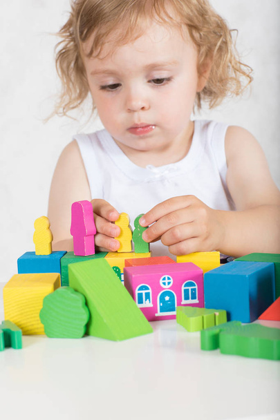 Mała dziewczynka dwóch lat buduje coś z kolorowych figur geometrycznych i kształty. Zbliżenie - Zdjęcie, obraz