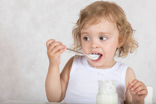 La bambina di due anni sta mangiando yogurt naturale senza zucchero. Primo piano
 - Foto, immagini