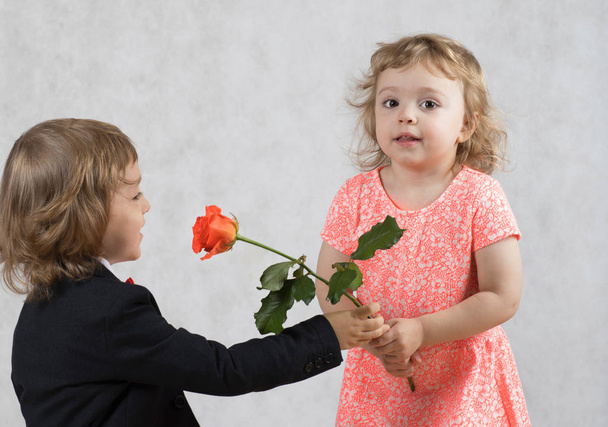 Vierjähriger Junge überreicht dem Mädchen eine Rose - Foto, Bild