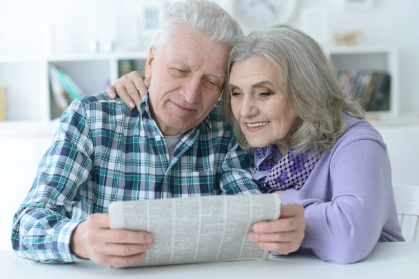Close-up portrait of a  senior couple with newspaper  at home  - Fotó, kép