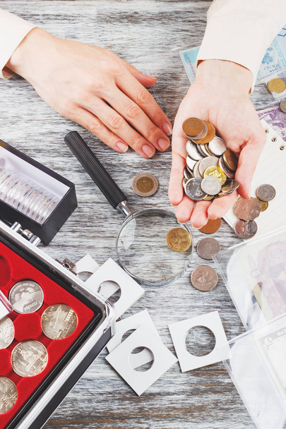 Hands with a magnifying glass, coins and banknotes - Photo, Image