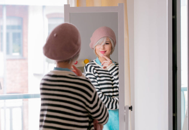 Mladá dívka v baret s krátkými vlasy oblékat se poblíž zrcadlo doma - Fotografie, Obrázek