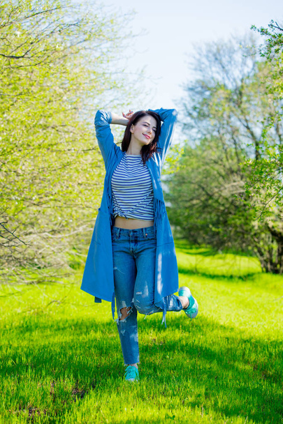 Jeune fille en vêtements bleus au jardin printanier. Journée ensoleillée
 - Photo, image